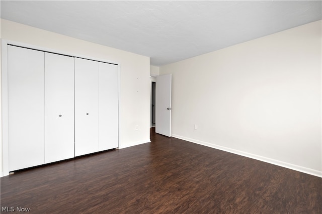 unfurnished bedroom with a closet and dark hardwood / wood-style flooring