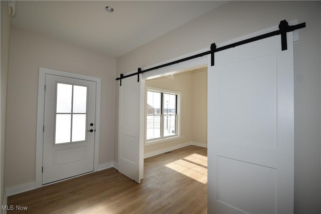 entryway with a barn door and hardwood / wood-style floors