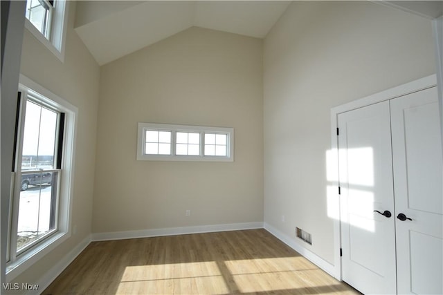 unfurnished room with a wealth of natural light, light hardwood / wood-style flooring, and high vaulted ceiling