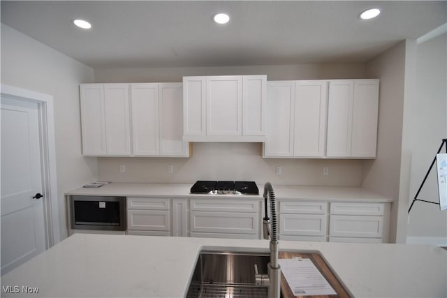 kitchen with sink, gas stovetop, and white cabinets