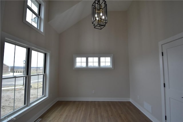 spare room featuring high vaulted ceiling, plenty of natural light, wood finished floors, and baseboards