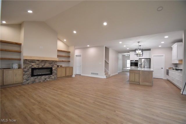 interior space with open floor plan, appliances with stainless steel finishes, a center island with sink, and visible vents