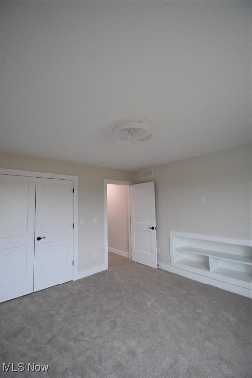 unfurnished bedroom with carpet floors, baseboards, visible vents, and a closet