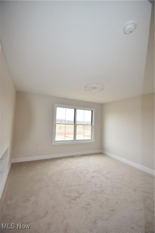 spare room with light carpet and baseboards