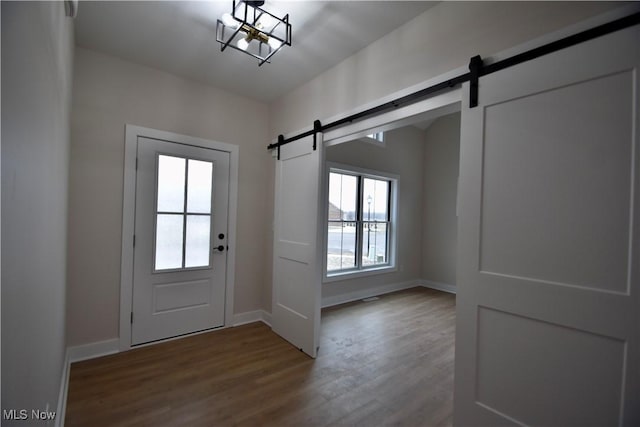 entryway featuring a barn door, baseboards, and dark wood finished floors