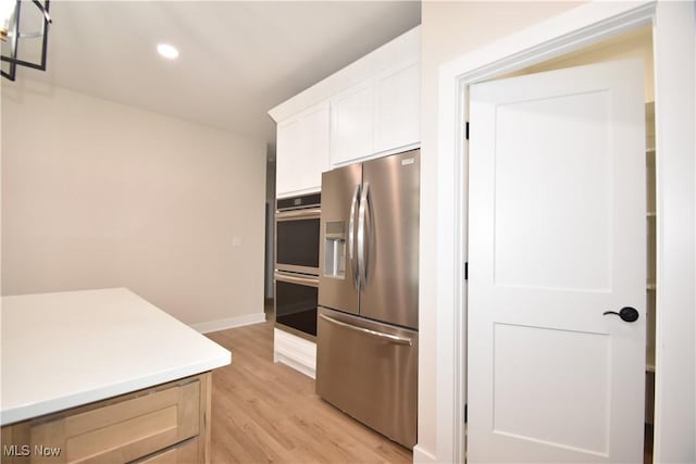 kitchen with white cabinets, light wood-style flooring, appliances with stainless steel finishes, light countertops, and recessed lighting