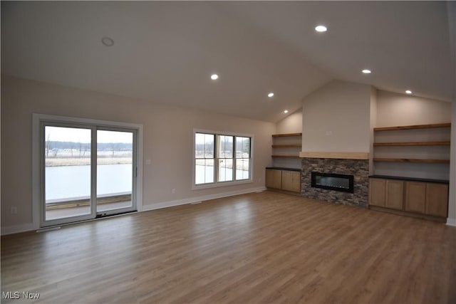 unfurnished living room featuring a water view, light wood-style floors, a fireplace, and baseboards