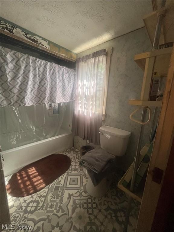 bathroom with toilet, shower / bath combo, and a textured ceiling