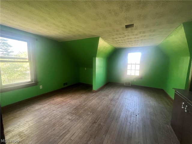 bonus room with a textured ceiling, baseboards, vaulted ceiling, and hardwood / wood-style floors