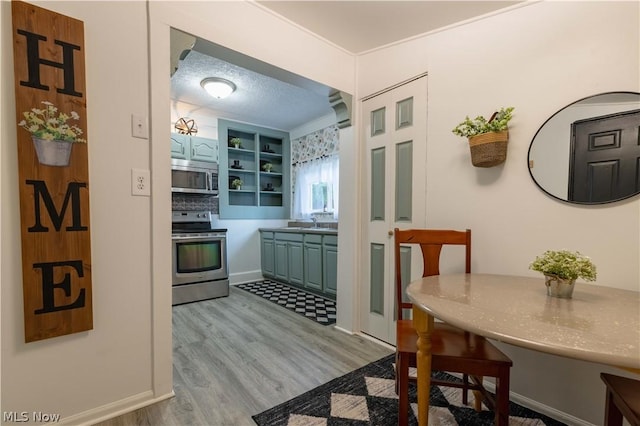 kitchen with sink, light hardwood / wood-style flooring, a textured ceiling, and appliances with stainless steel finishes