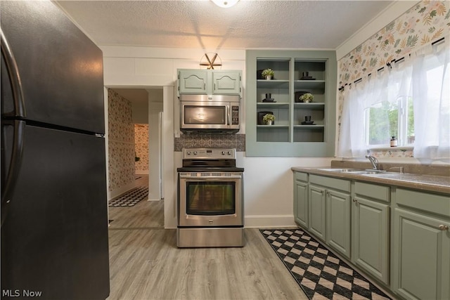 kitchen featuring sink, stainless steel appliances, a textured ceiling, and light wood-type flooring