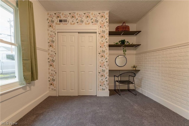 unfurnished bedroom with a textured ceiling, carpet floors, a closet, and crown molding