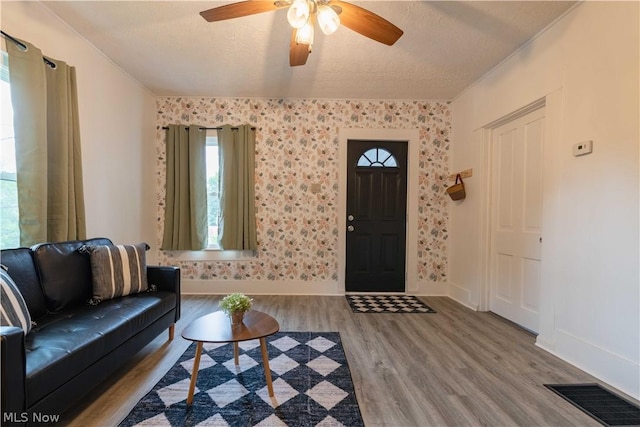 living room featuring ceiling fan, wood-type flooring, and a textured ceiling