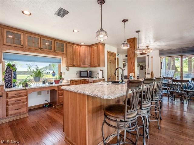 kitchen featuring hanging light fixtures, sink, an island with sink, and a healthy amount of sunlight