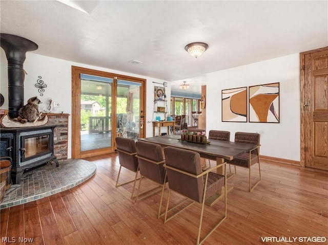 dining space with hardwood / wood-style flooring and a wood stove