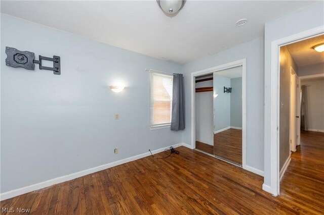 unfurnished bedroom featuring dark hardwood / wood-style floors and a closet