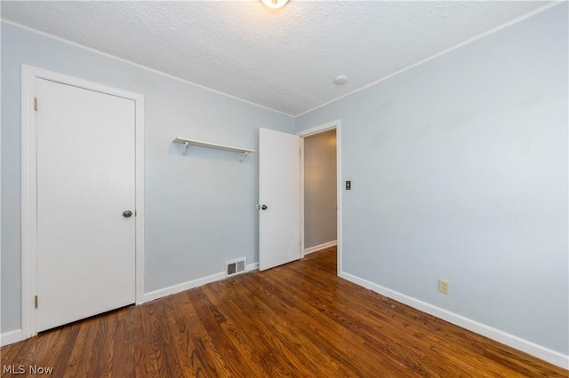 empty room featuring a textured ceiling and dark hardwood / wood-style floors