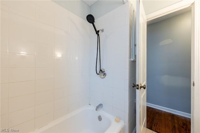 bathroom with hardwood / wood-style floors and tiled shower / bath