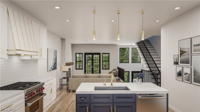 kitchen featuring stainless steel appliances, sink, white cabinetry, and decorative light fixtures