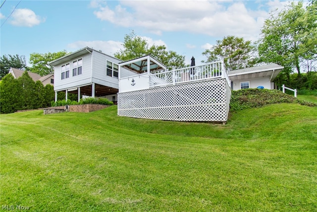 back of property with a deck and a lawn