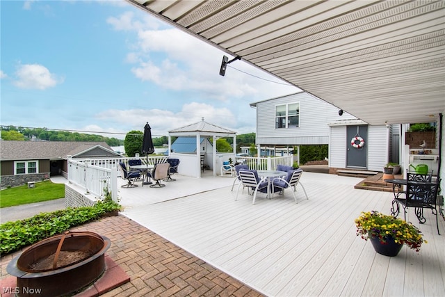 wooden terrace featuring a gazebo and a fire pit