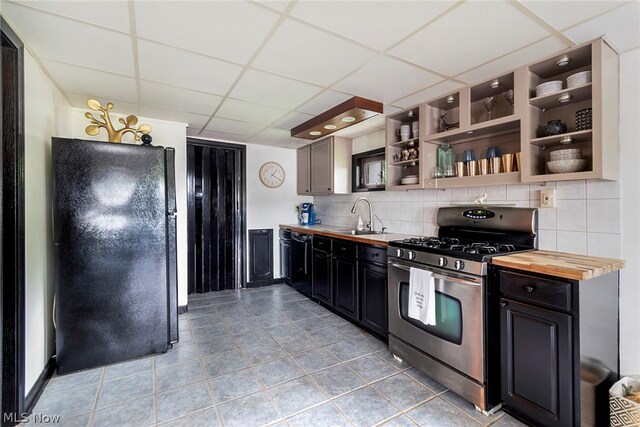 kitchen with backsplash, a paneled ceiling, black appliances, and wood counters