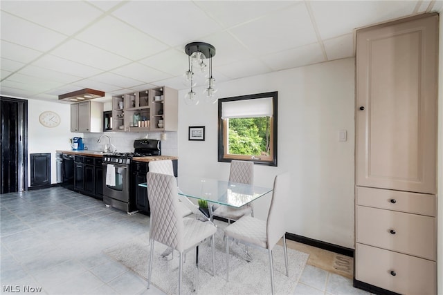 dining space featuring a paneled ceiling, sink, and light tile flooring