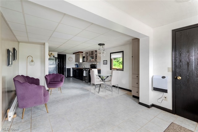 tiled living room featuring a baseboard radiator and a drop ceiling