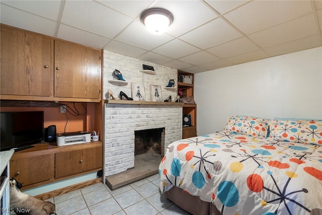 bedroom with a fireplace, a paneled ceiling, brick wall, and light tile floors