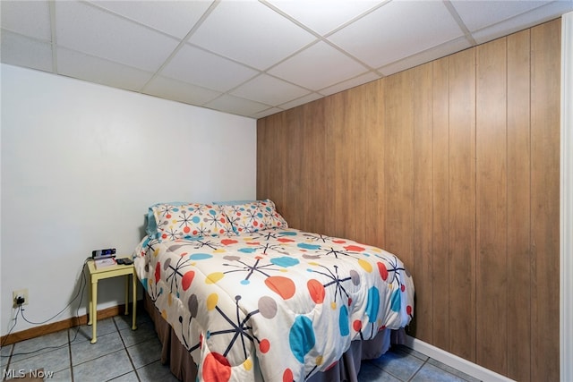 bedroom with a paneled ceiling and tile floors