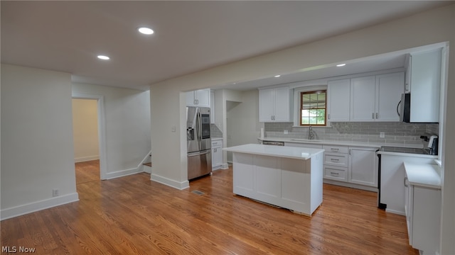 kitchen featuring appliances with stainless steel finishes, light hardwood / wood-style floors, a center island, and white cabinetry