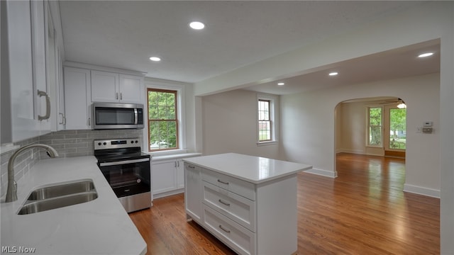 kitchen with appliances with stainless steel finishes, sink, a kitchen island, and light hardwood / wood-style flooring