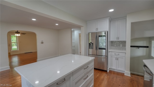 kitchen featuring light hardwood / wood-style floors, tasteful backsplash, ceiling fan, and stainless steel appliances