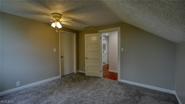 bonus room with a textured ceiling, lofted ceiling, dark colored carpet, and ceiling fan