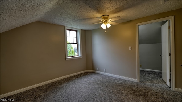 interior space with a textured ceiling, lofted ceiling, ceiling fan, and dark carpet