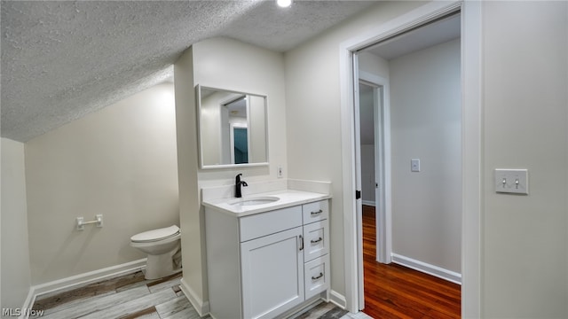 bathroom featuring wood-type flooring, oversized vanity, toilet, and a textured ceiling