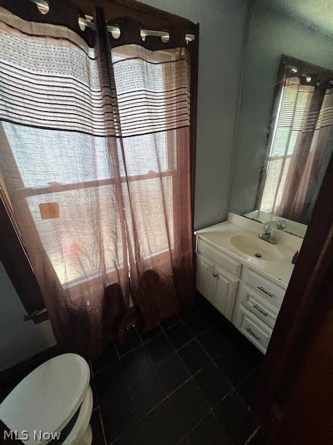 bathroom with tile flooring, large vanity, and toilet