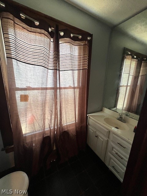 bathroom featuring tile flooring, vanity, toilet, and a textured ceiling