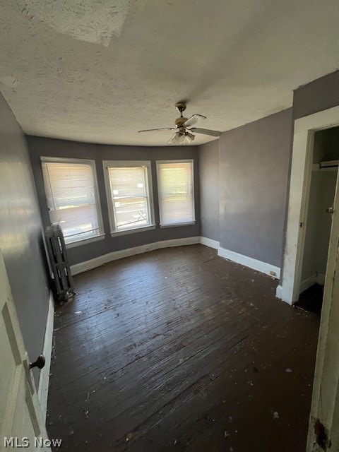 spare room featuring a textured ceiling, radiator, ceiling fan, and dark hardwood / wood-style flooring