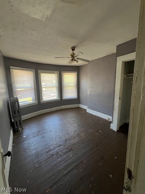 unfurnished room with radiator, ceiling fan, and dark hardwood / wood-style flooring