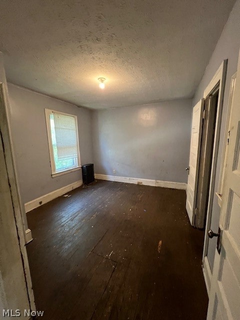 empty room featuring dark hardwood / wood-style floors and a textured ceiling