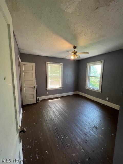 unfurnished room featuring dark wood-type flooring, ceiling fan, and a textured ceiling