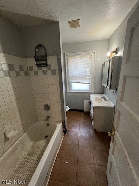 full bathroom with tiled shower / bath combo, vanity, toilet, and tile floors