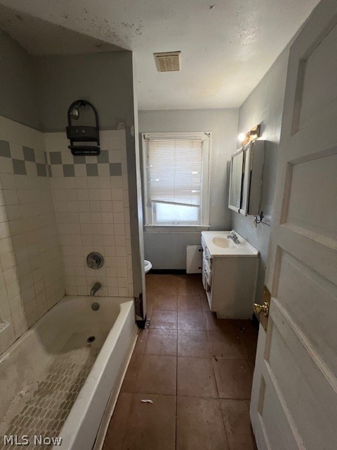 full bathroom featuring tile floors, tiled shower / bath, vanity, and toilet