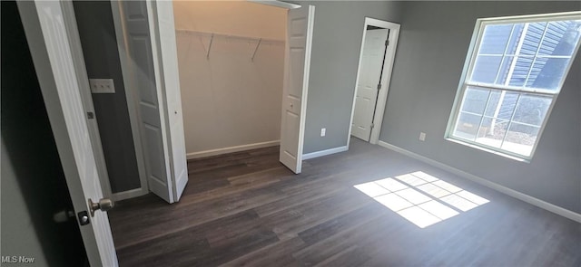 unfurnished bedroom featuring baseboards and dark wood-type flooring