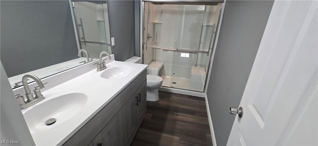 full bathroom featuring a sink, wood finished floors, toilet, and a stall shower
