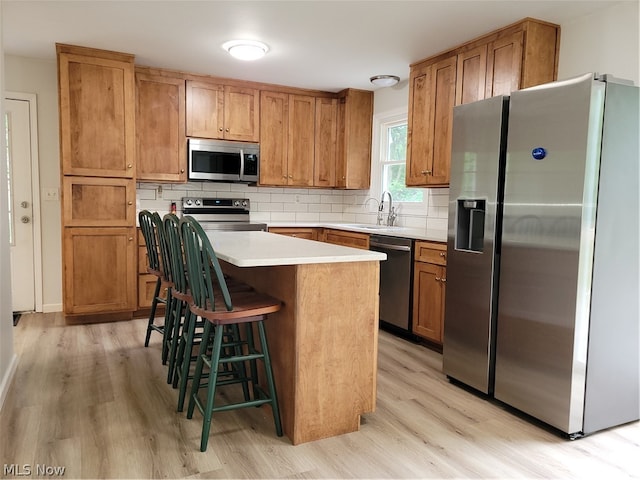 kitchen featuring appliances with stainless steel finishes, backsplash, and light wood-type flooring