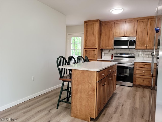 kitchen with light hardwood / wood-style flooring, backsplash, a kitchen breakfast bar, a center island, and electric range oven