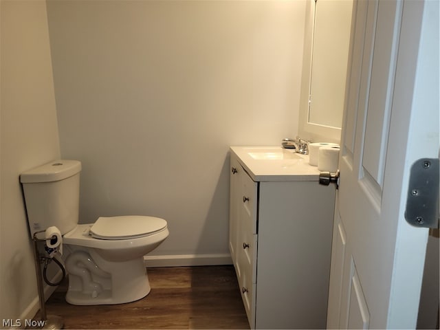 bathroom with toilet, vanity, and hardwood / wood-style flooring