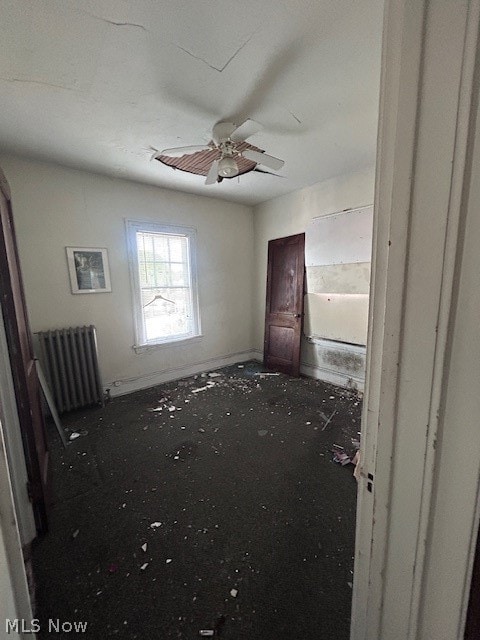 empty room with ceiling fan and radiator heating unit